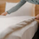 A housekeeper in a uniform makes a bed preparing luxury hotel room for guests cleaning and travel concept