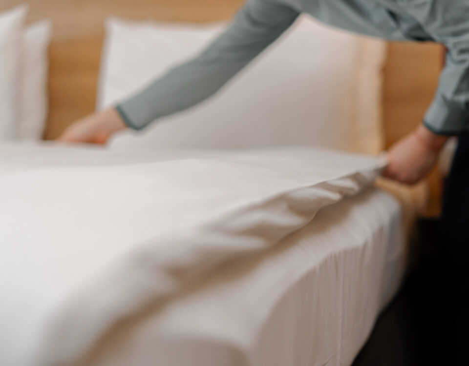 A housekeeper in a uniform makes a bed preparing luxury hotel room for guests cleaning and travel concept